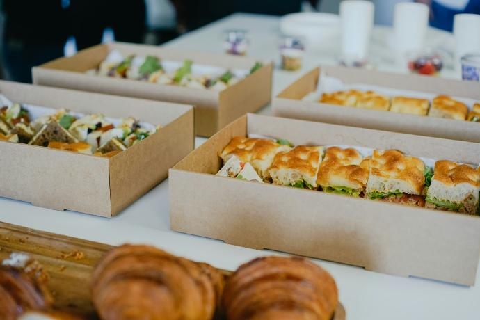 a table topped with boxes of sandwiches and pastries